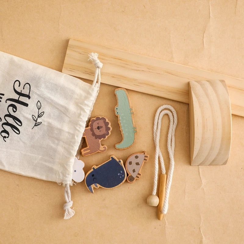 Wooden toy set with animal shapes on a beige surface, including a drawstring bag labeled 'Hello'.