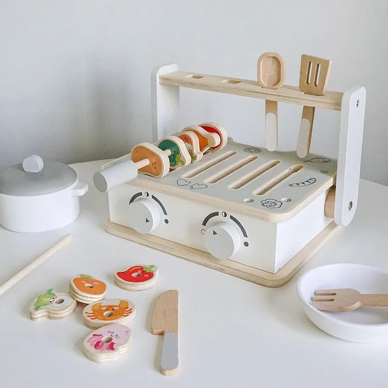 Wooden toy kitchen set with various utensils and food items on a white surface.